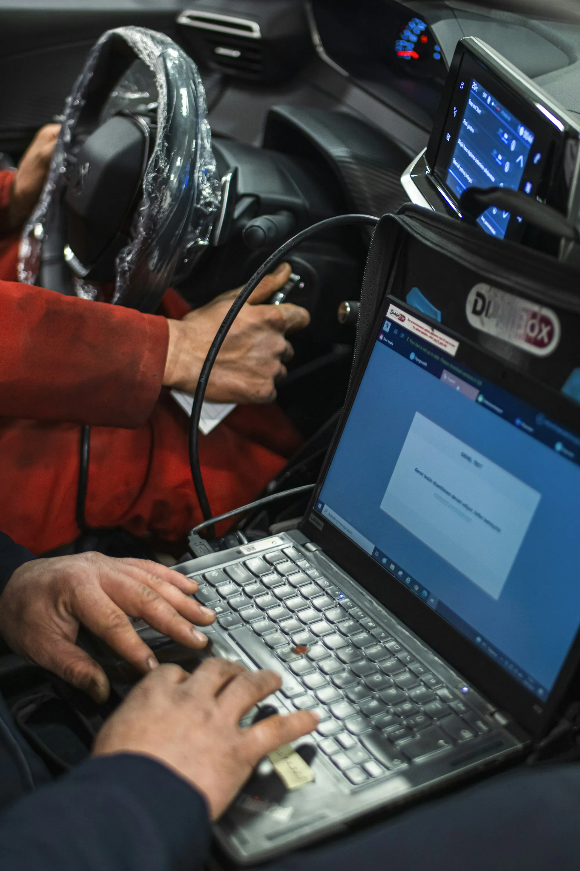 Technician entering data on a laptop connected to a vehicle