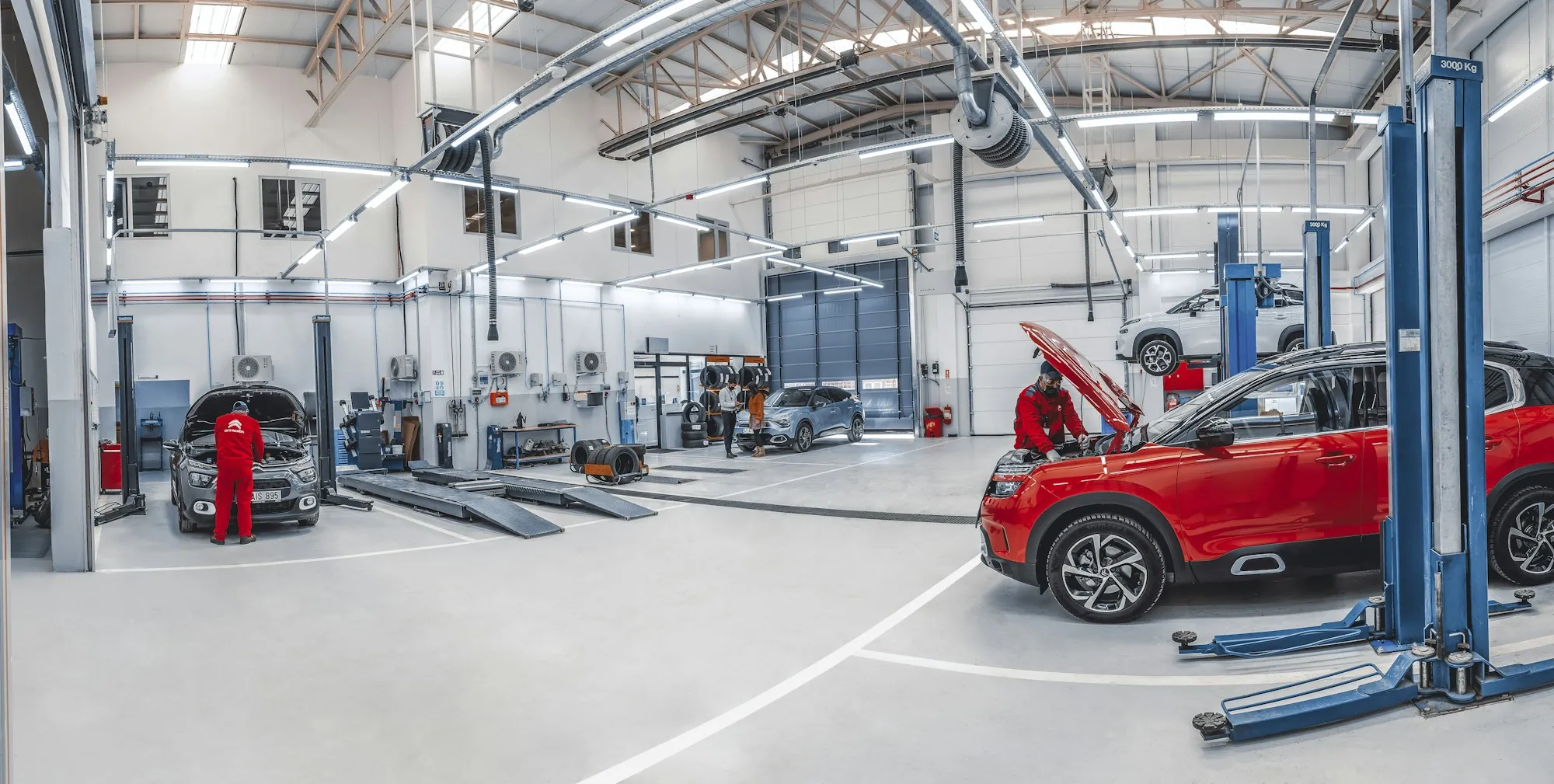 Clean repair shop floor with vehicles raised on blue lifts