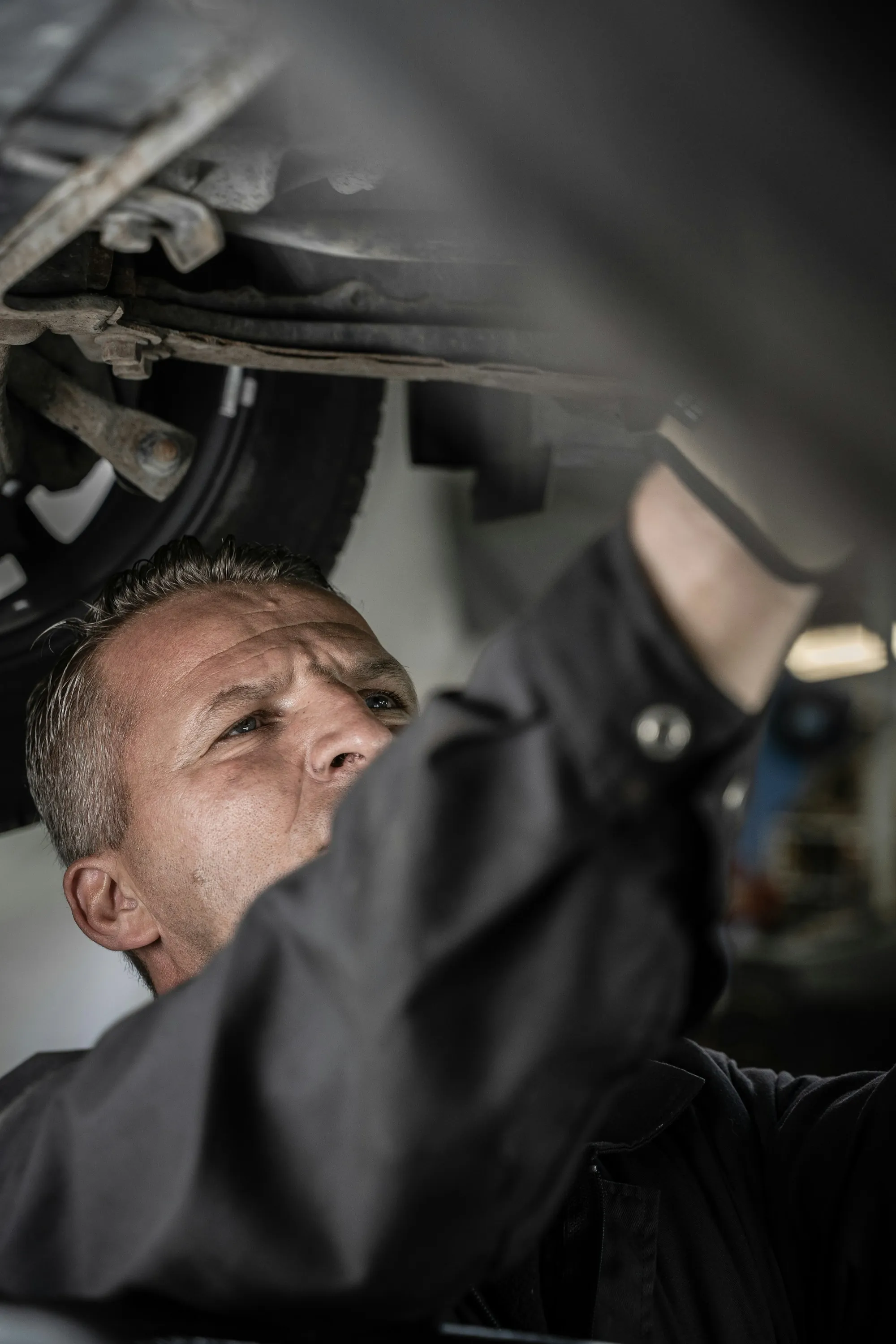 Mechanic in a dark shirt working beneath a vehicle